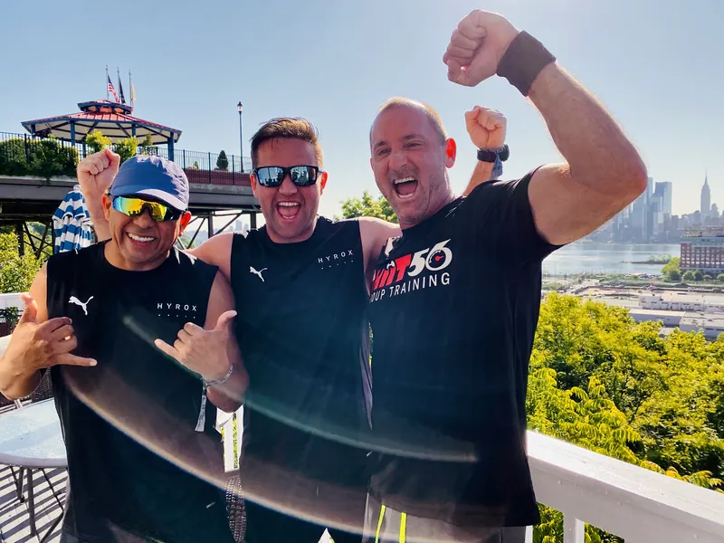 Three members of the HIIT56 training crew celebrating together in New York